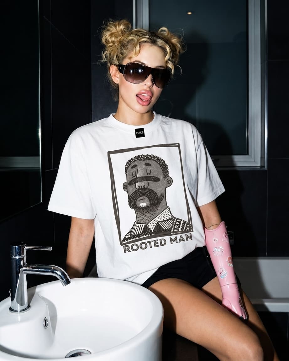 Model in a white Rooted Man t-shirt seated on a bathroom sink